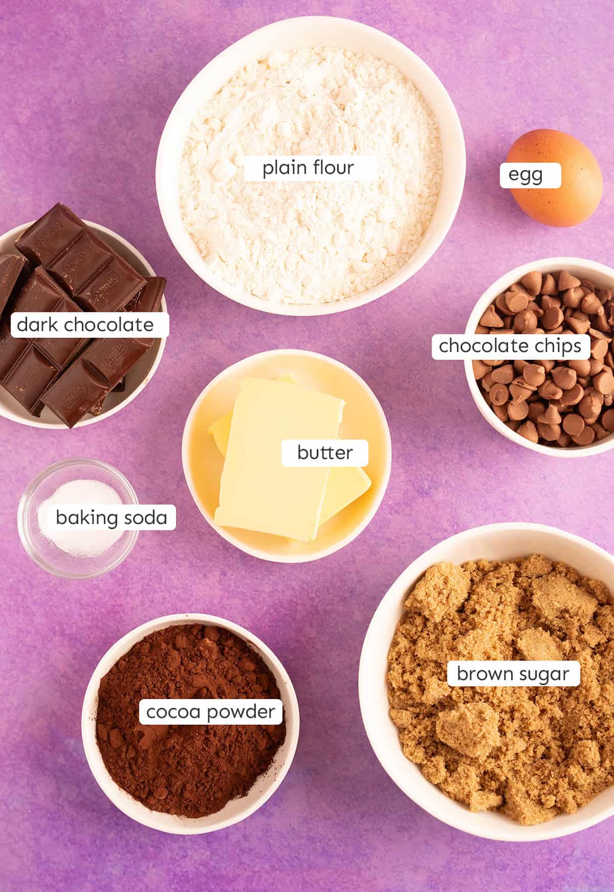 All the ingredients needed to make Chocolate NYC Cookies on a purple backdrop.