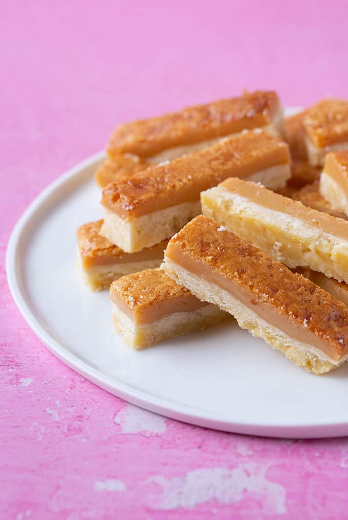 A plate of caramel covered shortbread on a pink background