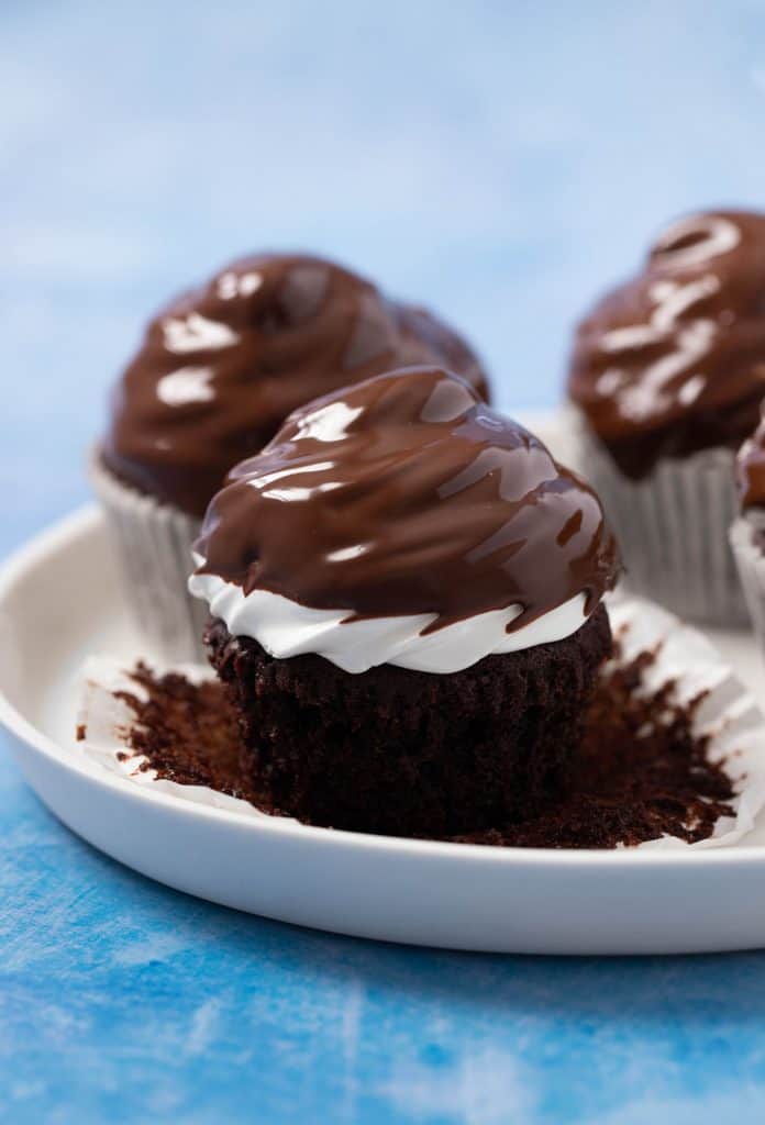 A plate of homemade Chocolate Marshmallow Cupcakes dipped in chocolate