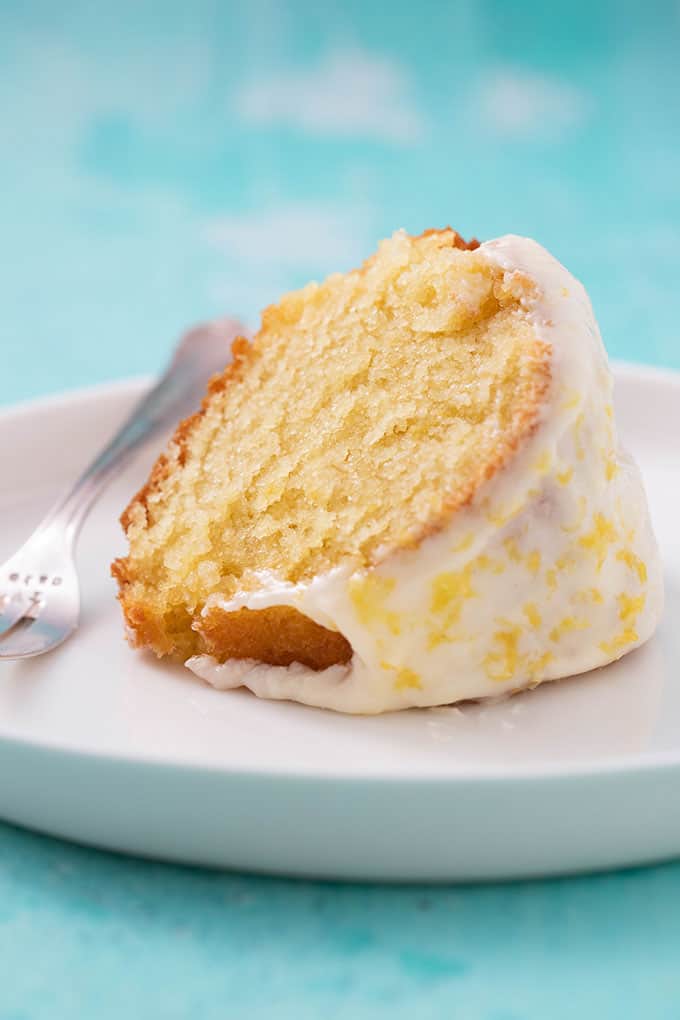 Close up of a slice of homemade Glazed Lemon Bundt Cake on a white cake plate