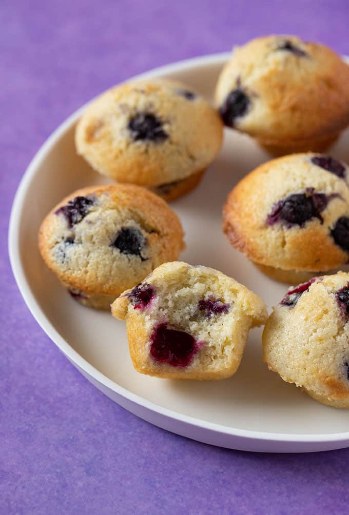 A plate of Mini Blueberry Muffins with a bite take out of one
