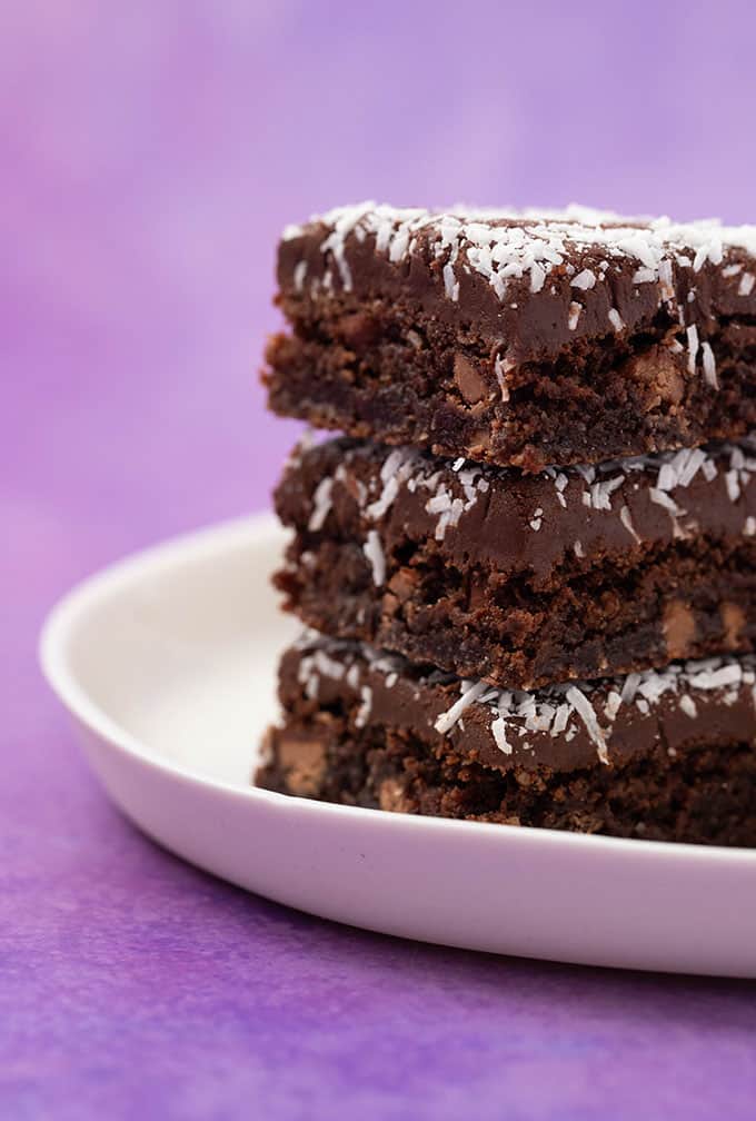 A stack of homemade Chocolate Coconut Slices on a white plate