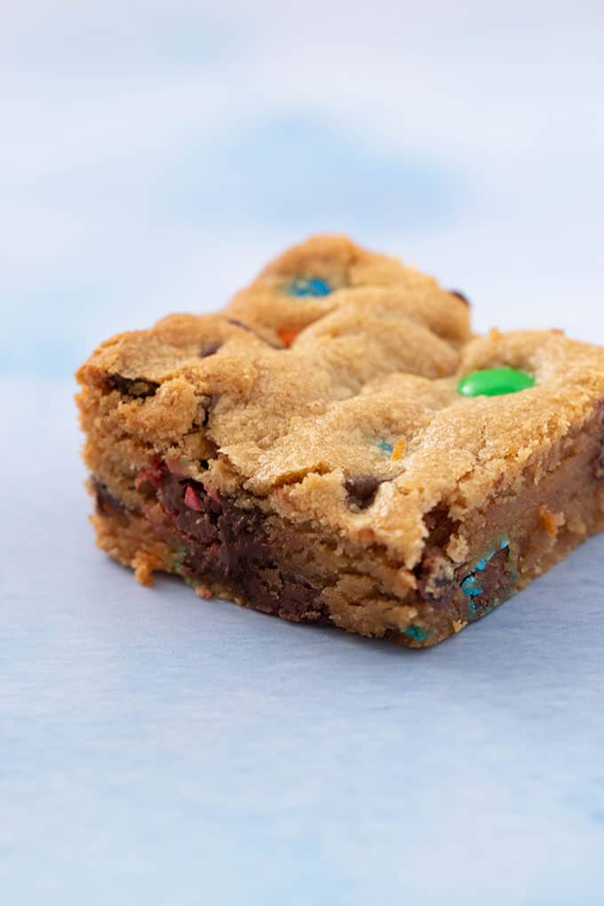 A close up of a peanut butter bar with chocolate chips and M&M's