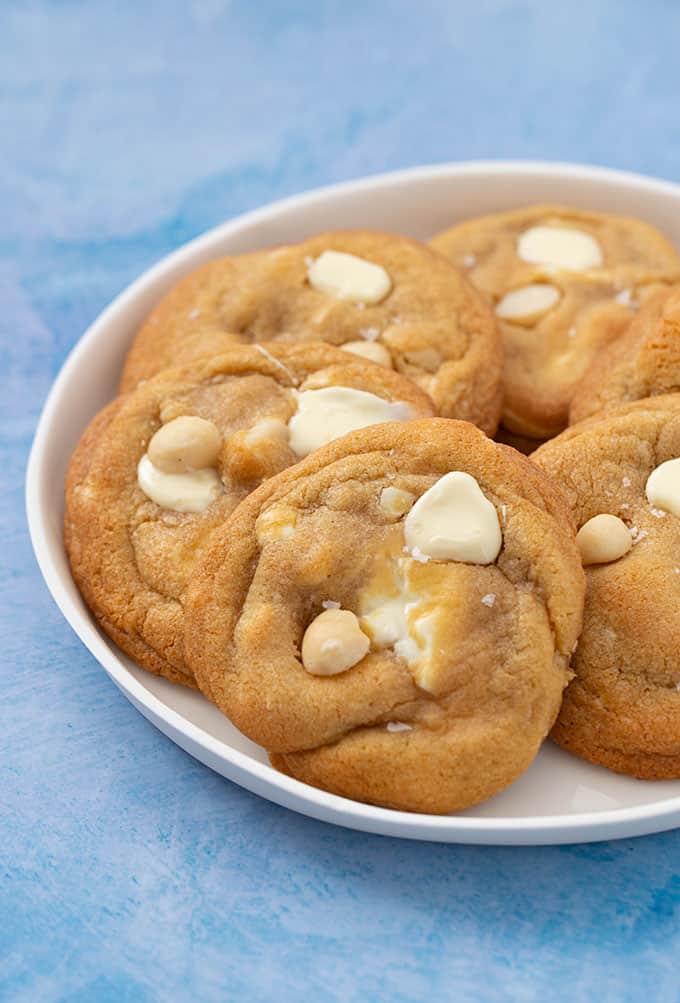 Homemade White Chocolate and Macadamia Cookies on a white plate with a blue background