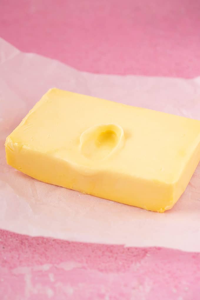 A block of butter with a thumbprint in it, indicating that it is soft enough to use. 