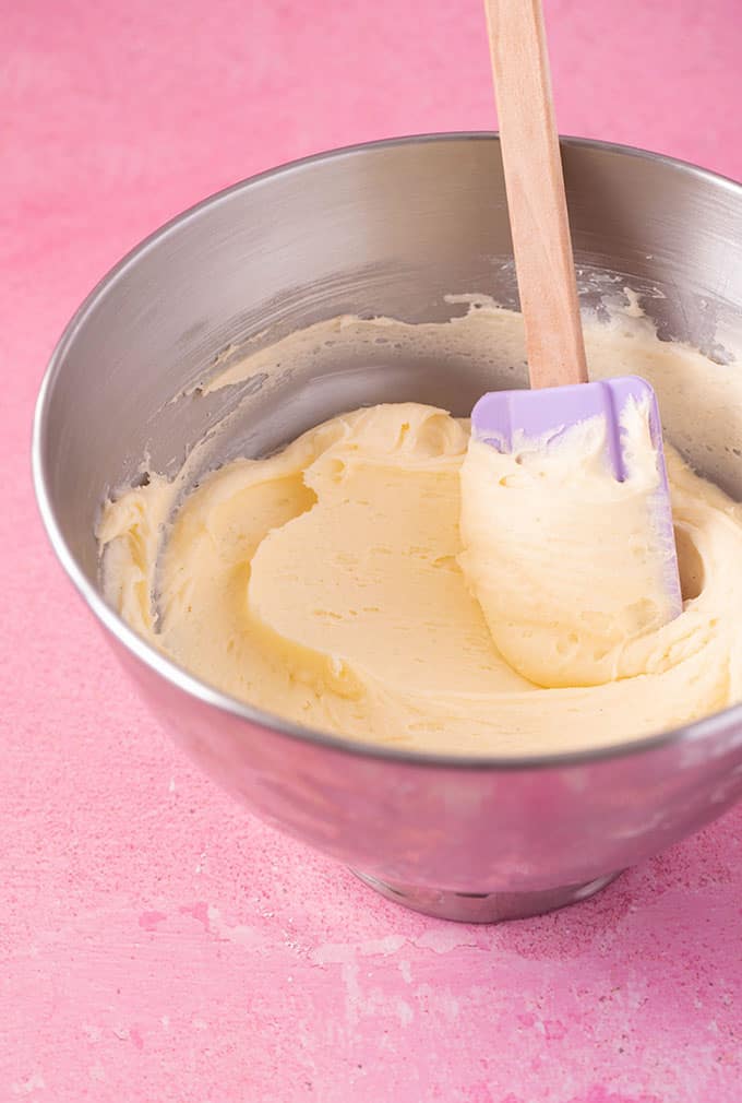 A bowl of buttercream with a purple spatula