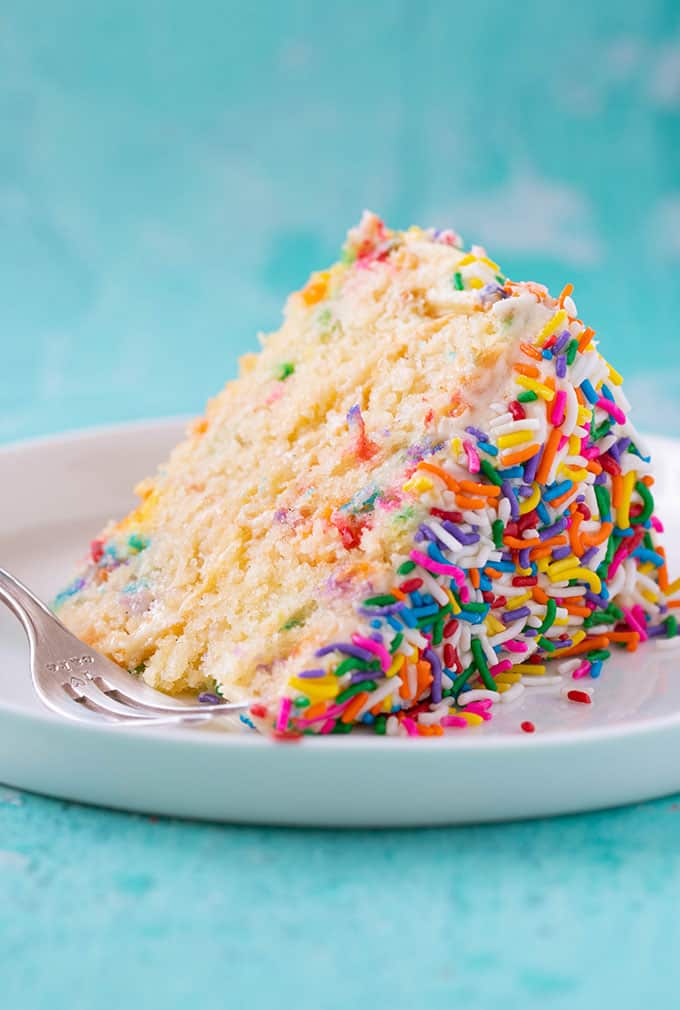 A big slice of funfetti vanilla layer cake on a white plate
