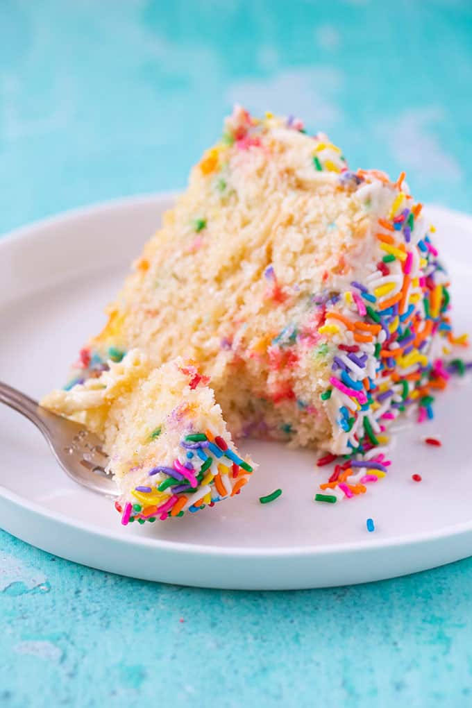 A piece of Funfetti Vanilla Layer Cake with a fork stuck in it