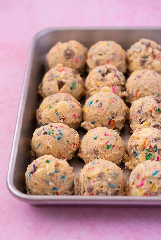 Balls of funfetti cookie dough on a silver baking tray