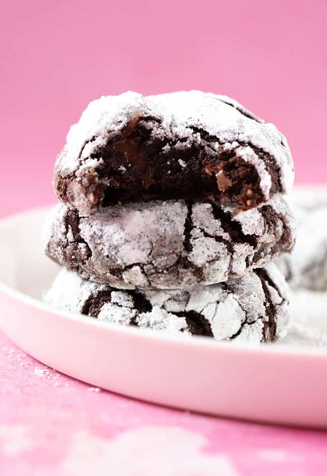 A stack of homemade Chocolate Crinkle Cookies with a pink background