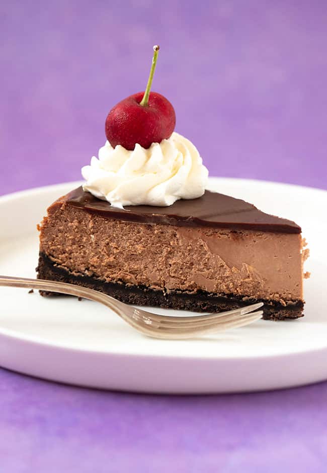 A slice of Baked Chocolate Cheesecake on a purple background