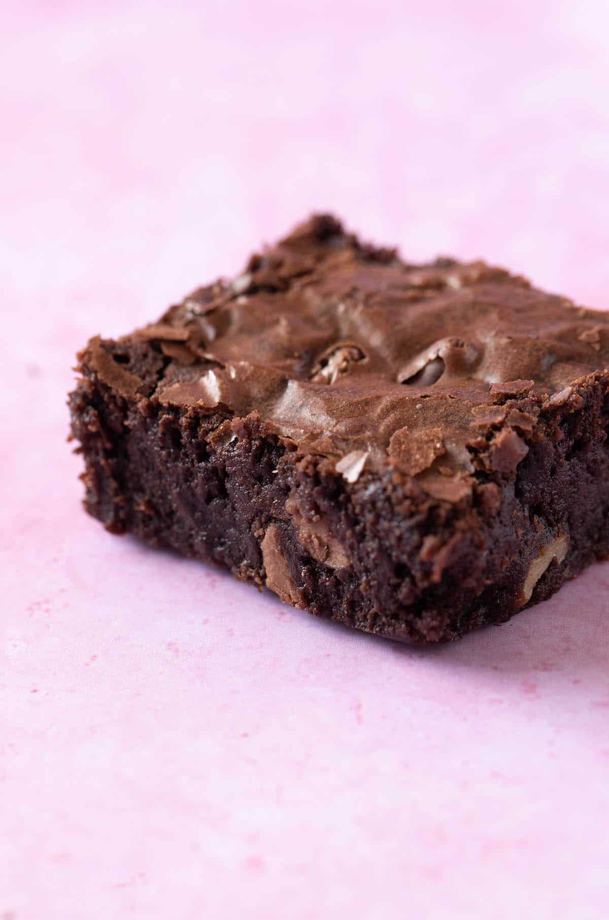 Close up of a fudgy brownie on a pink background