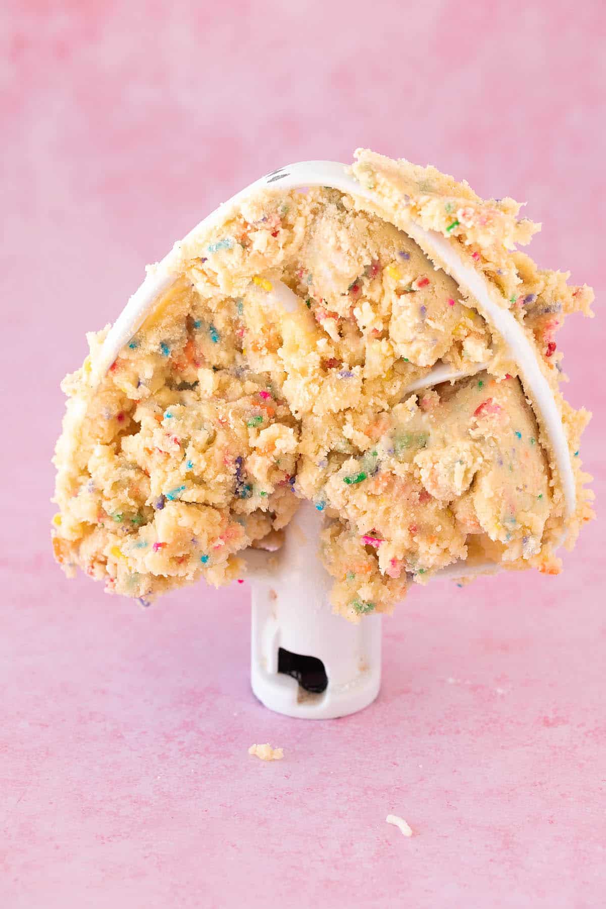 A paddle beater covered in Funfetti cookie dough