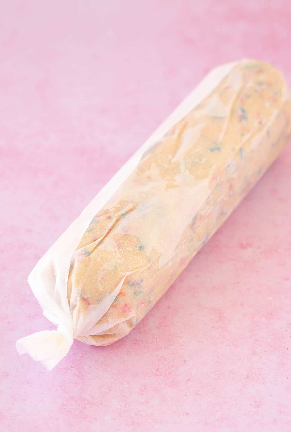 A roll of butter cookie dough wrapped in baking paper