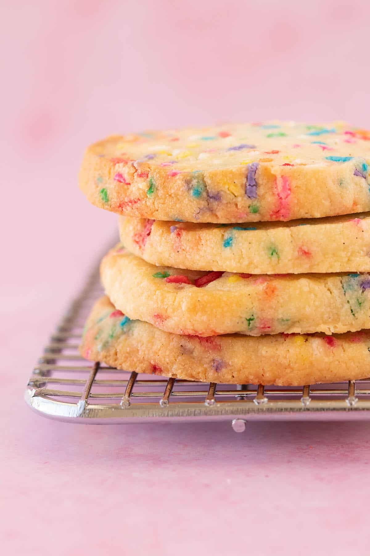 A stack of homemade Birthday Cake Butter Cookies on a pink background