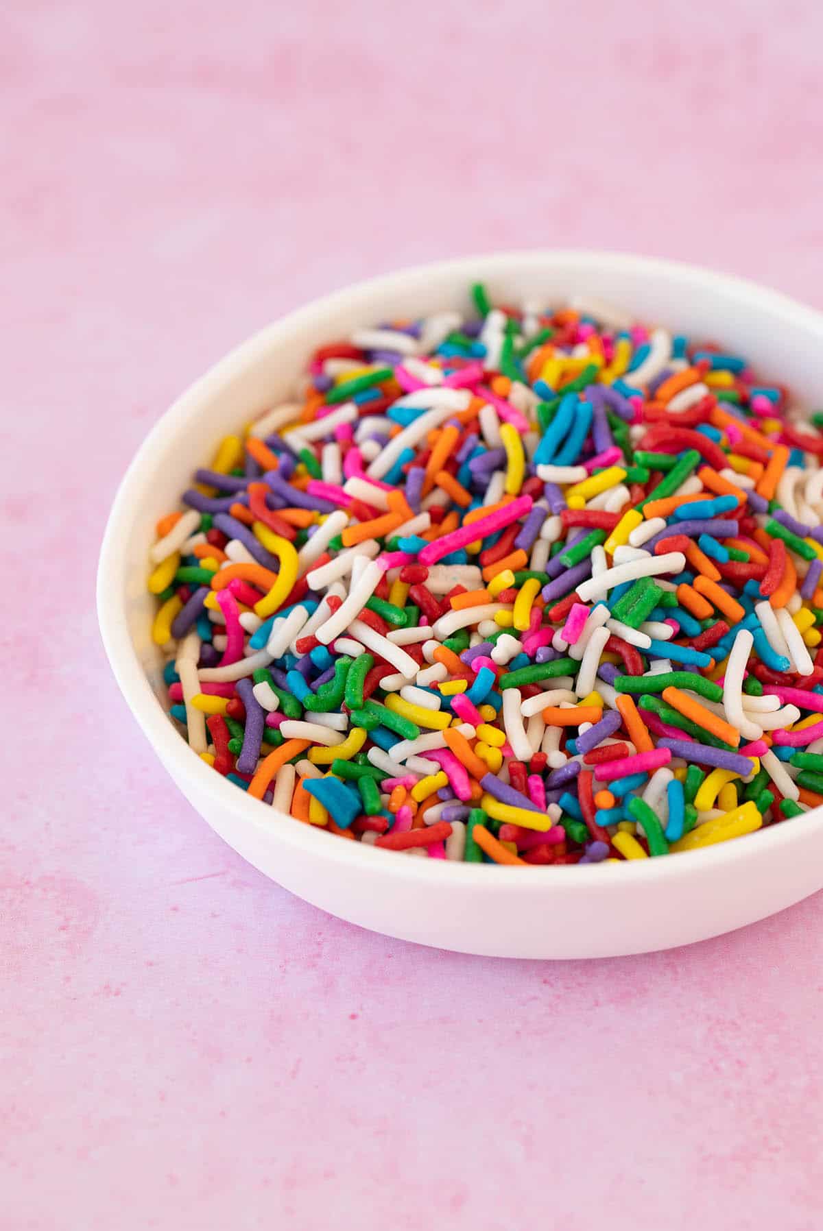 A white bowl filled with rainbow sprinkles