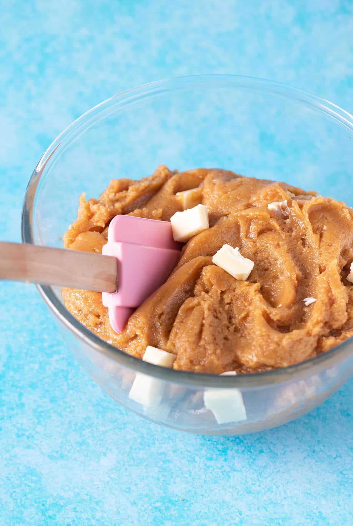 A glass bowl of blondies batter and a pink spatula
