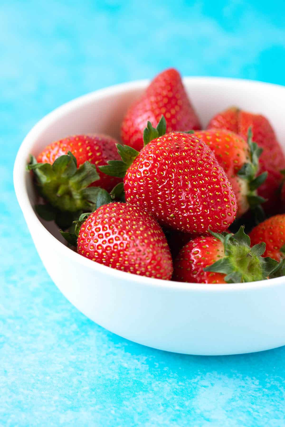 A white bowl filled with fresh strawberries