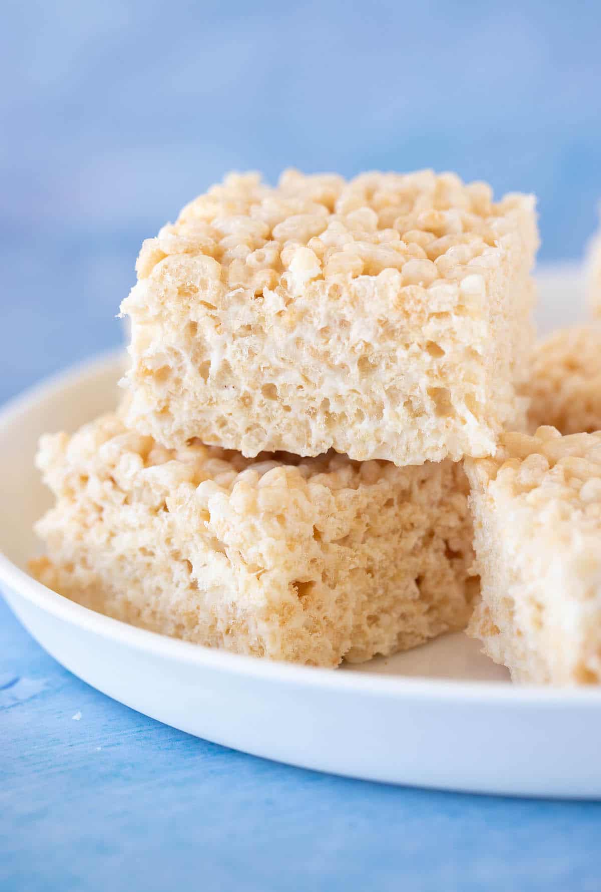 Close up shot of a plate of homemade Rice Krispie Treats on a blue background