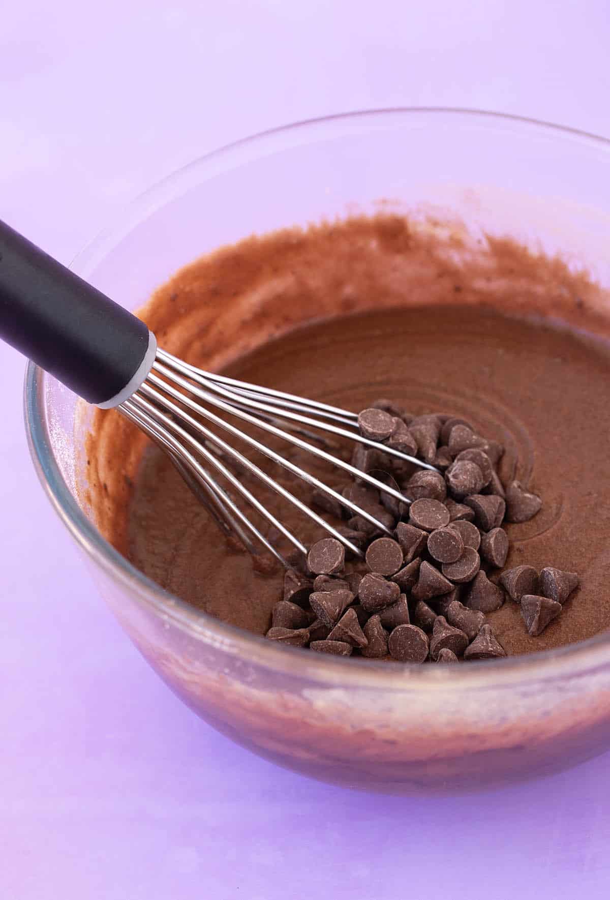 A glass bowl of chocolate Cocoa Brownies with a whisk 