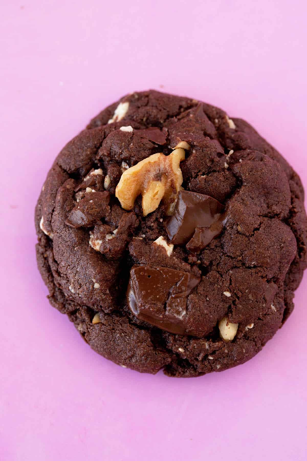 Top view of a chocolate cookie on a pink background