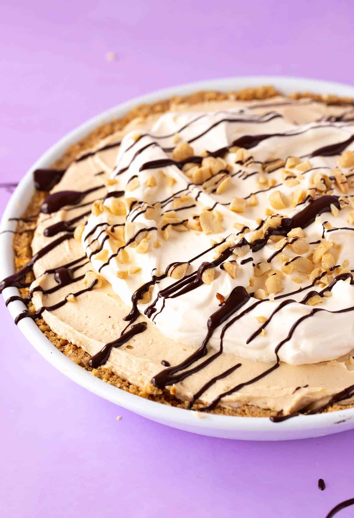 No bake Peanut Butter Pie topped with a drizzle of chocolate on a purple background 
