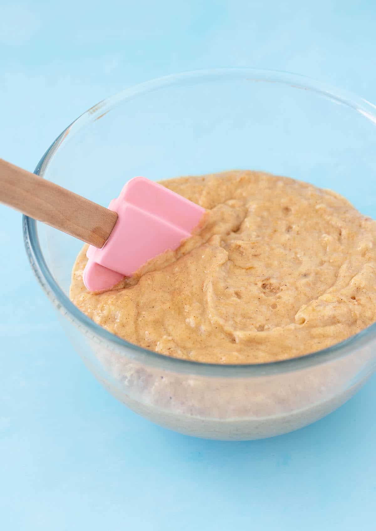 A glass mixing bowl filled with banana muffin batter