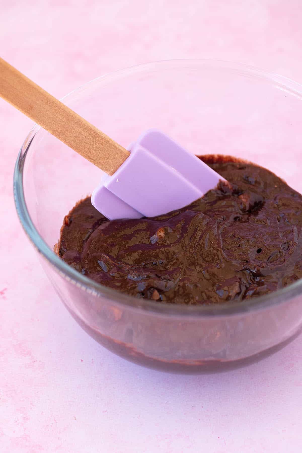 A glass mixing bowl filled with chocolate brownie batter