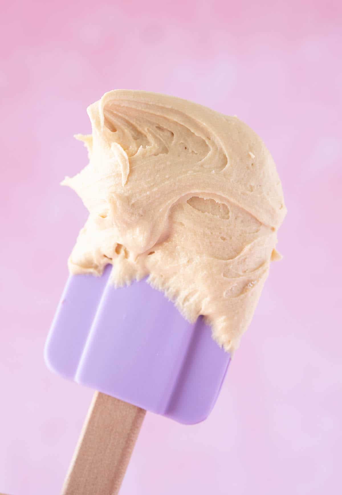 A purple spatula covered in Biscoff buttercream