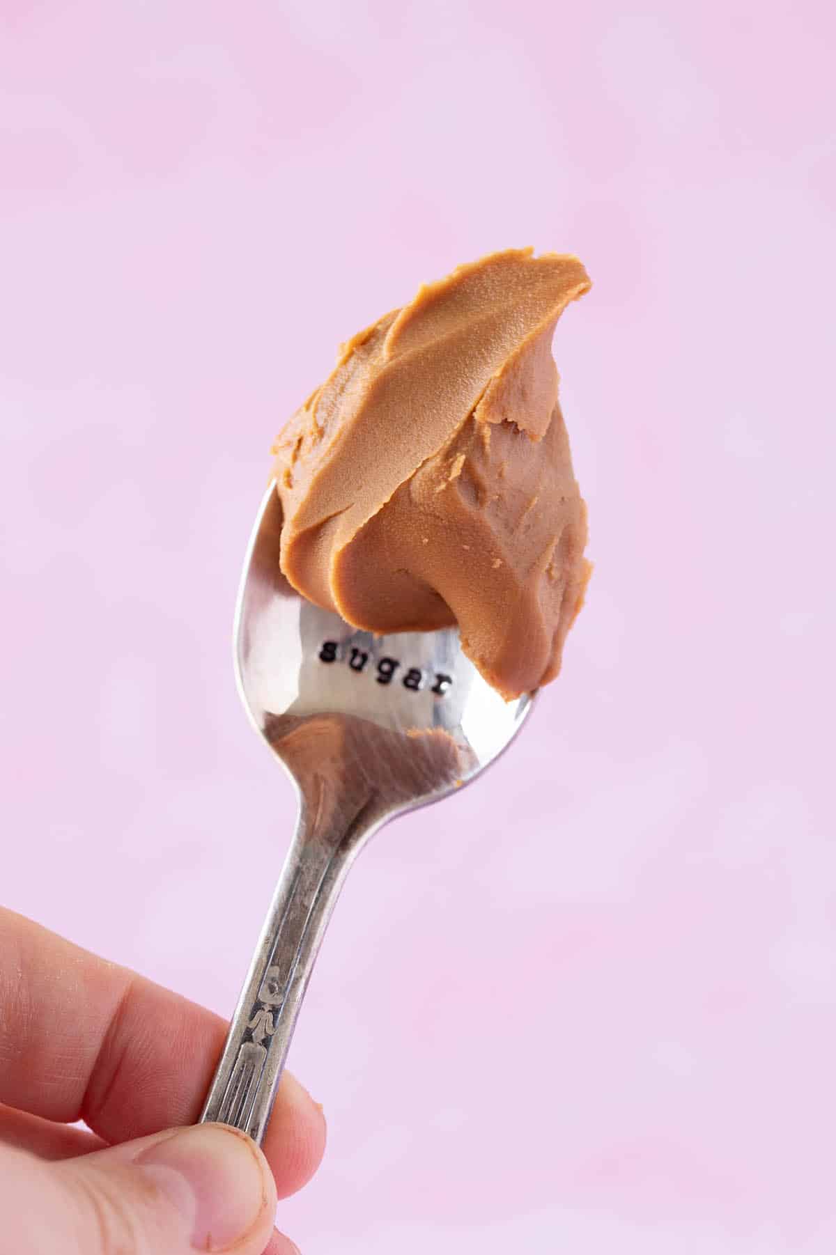 A hand holding a spoon that's full of Biscoff cookie spread