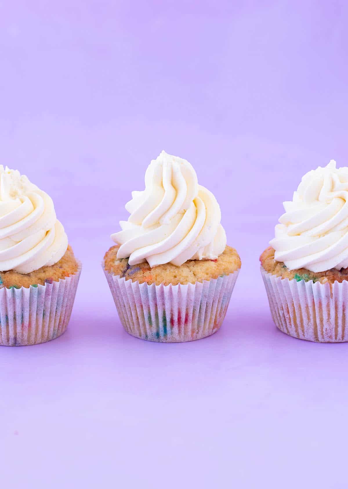 Three cupcakes frosted with big swirls of Swiss Meringue Buttercream.