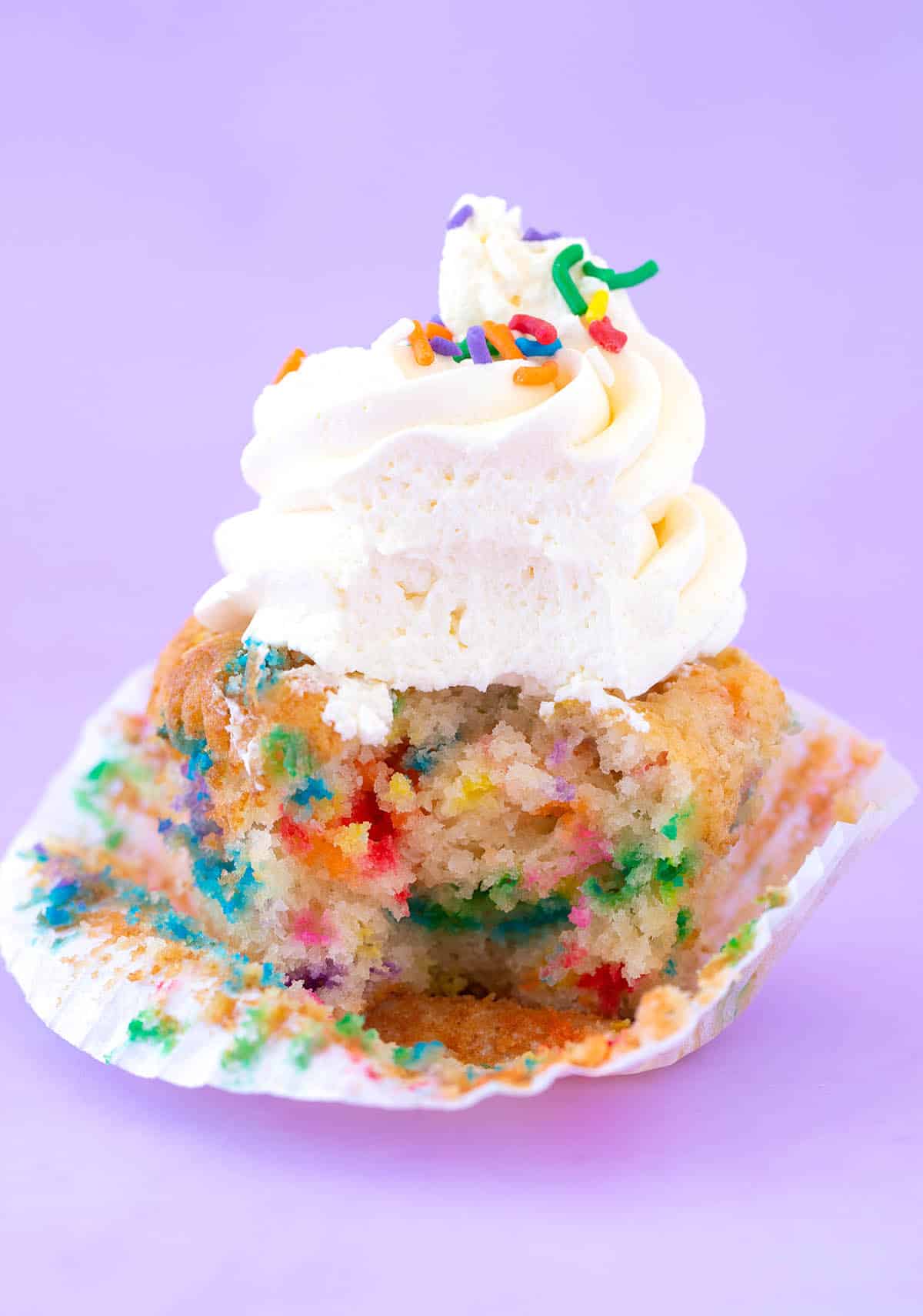 A homemade Funfetti Cupcakes with a bite taken out of it.