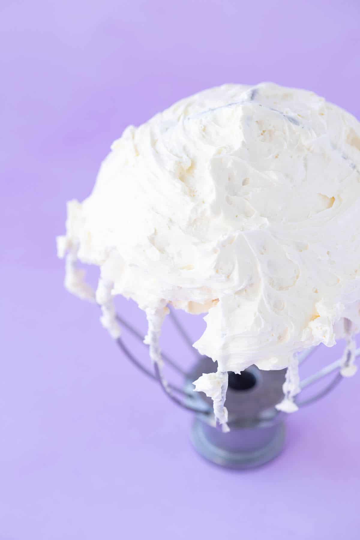 Close up shot of homemade Swiss Meringue Buttercream frosting on a purple background.