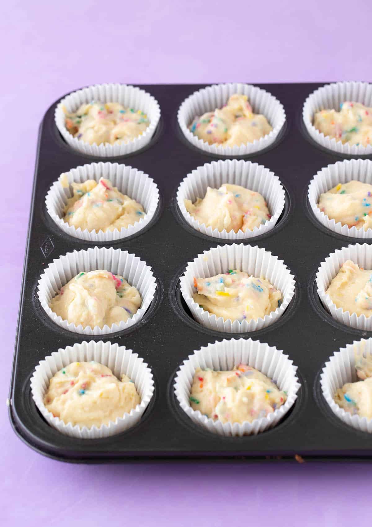 A muffin pan filled with funfetti cake batter.