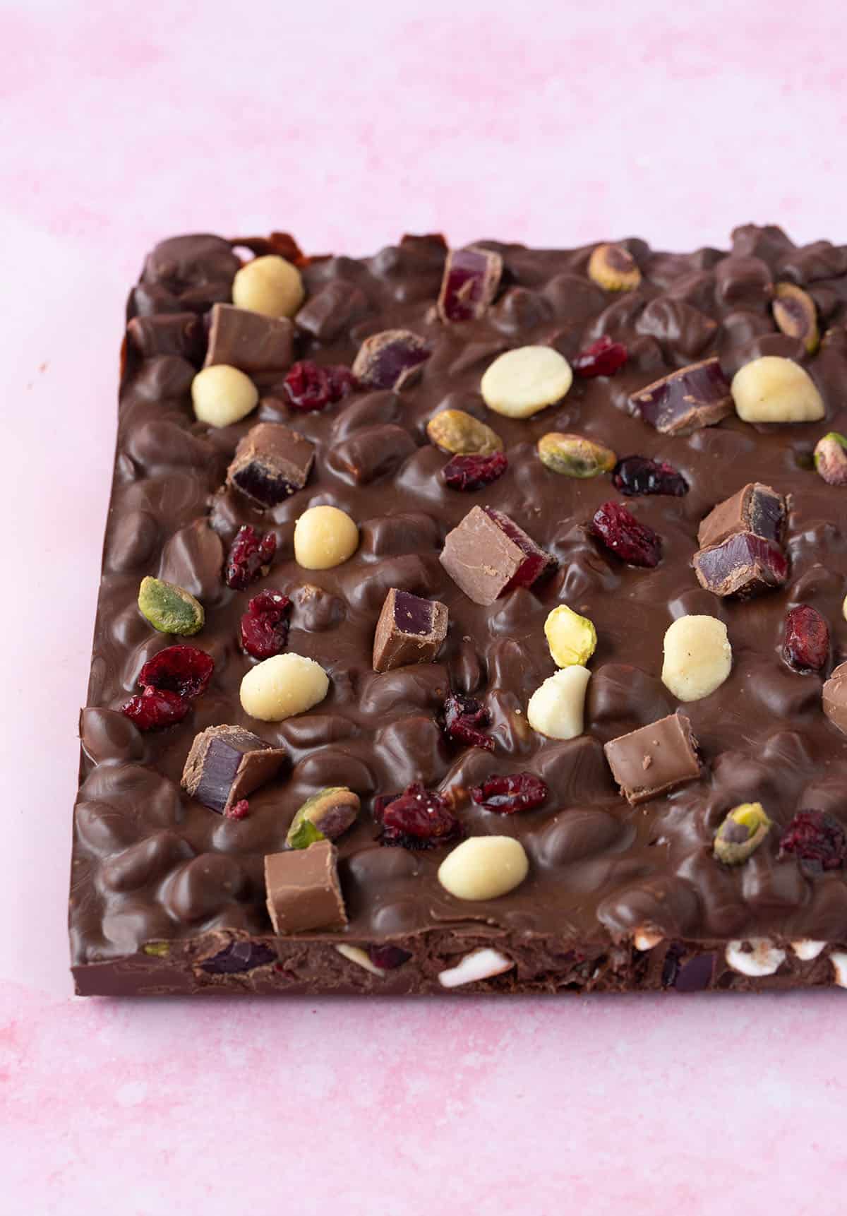 A big slab of homemade Christmas Rocky Road on a pink background.
