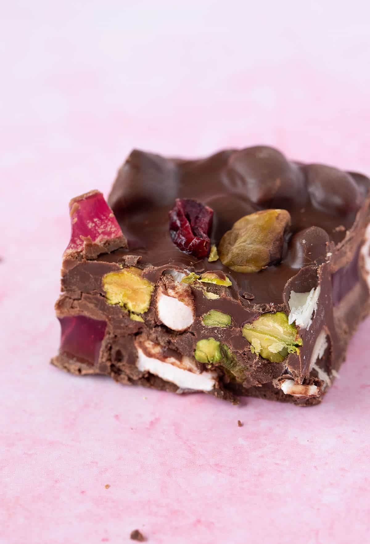Close up of a piece of Christmas Rocky Road on a pink background.