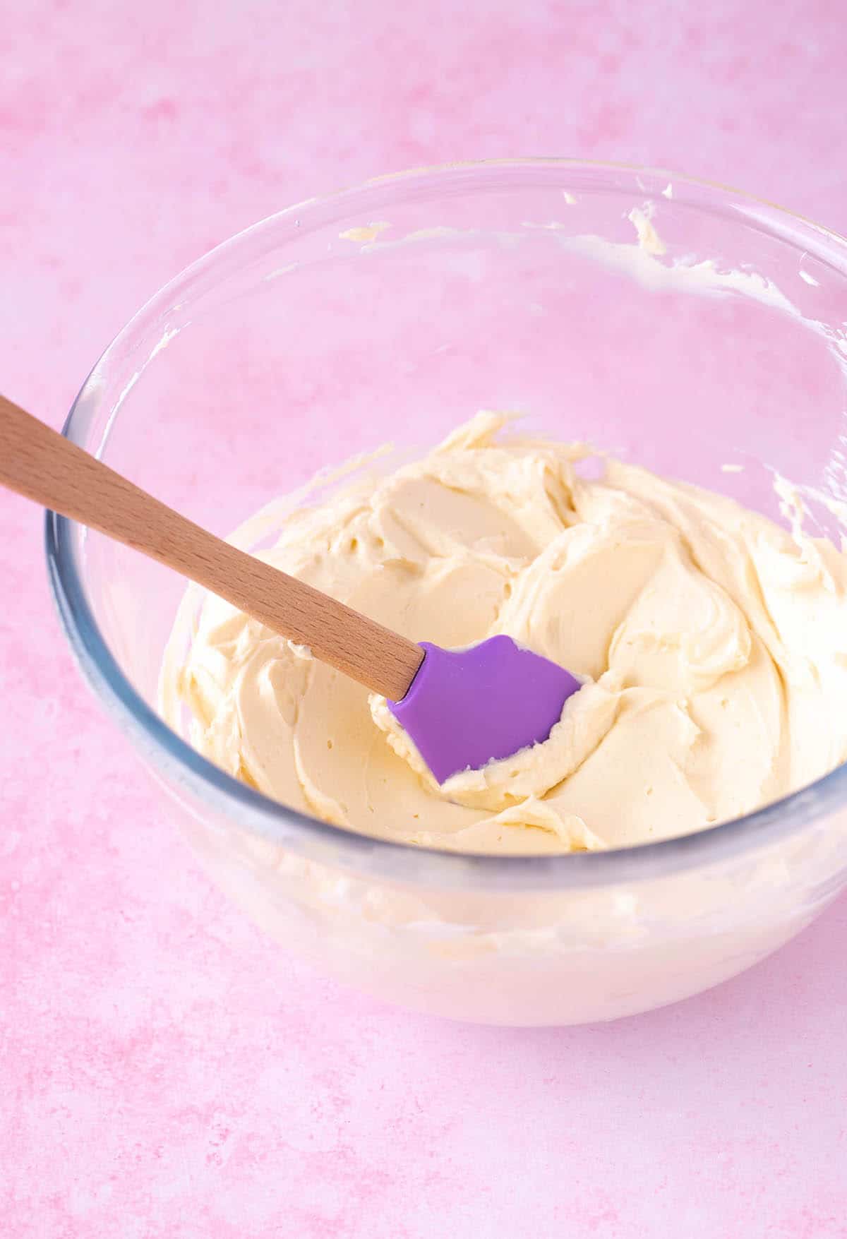 A glass bowl filled with cream cheese frosting.