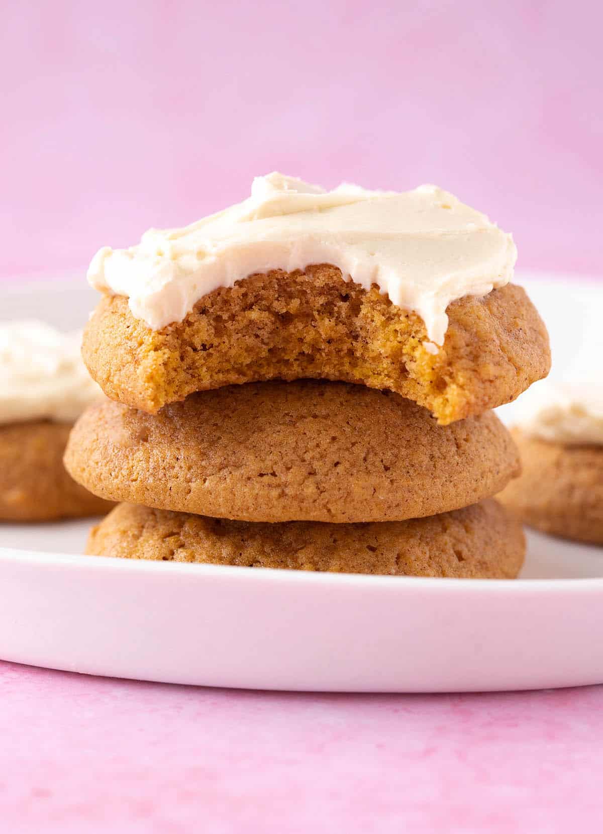 A stack of homemade Pumpkin Cookies topped with cream cheese frosting.