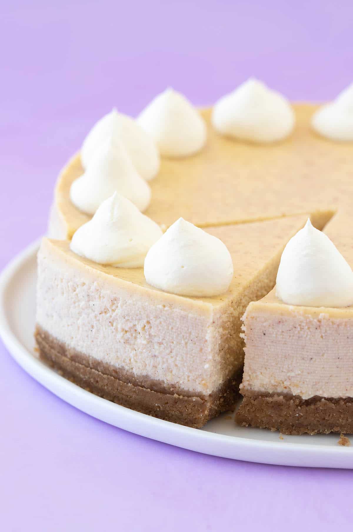 A beautiful Baked Eggnog Cheesecake with a slice taken out of it.