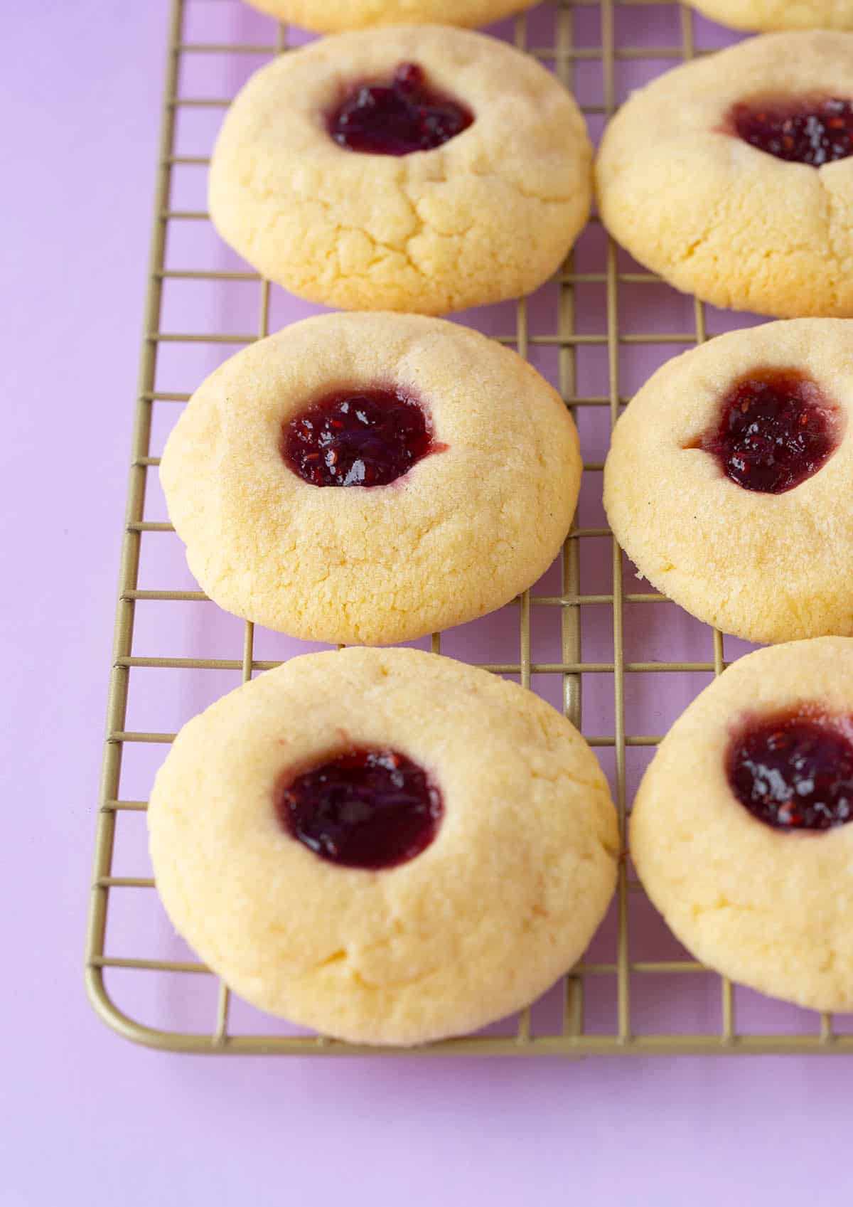Homemade thumbprint cookies sitting on a cooling rack