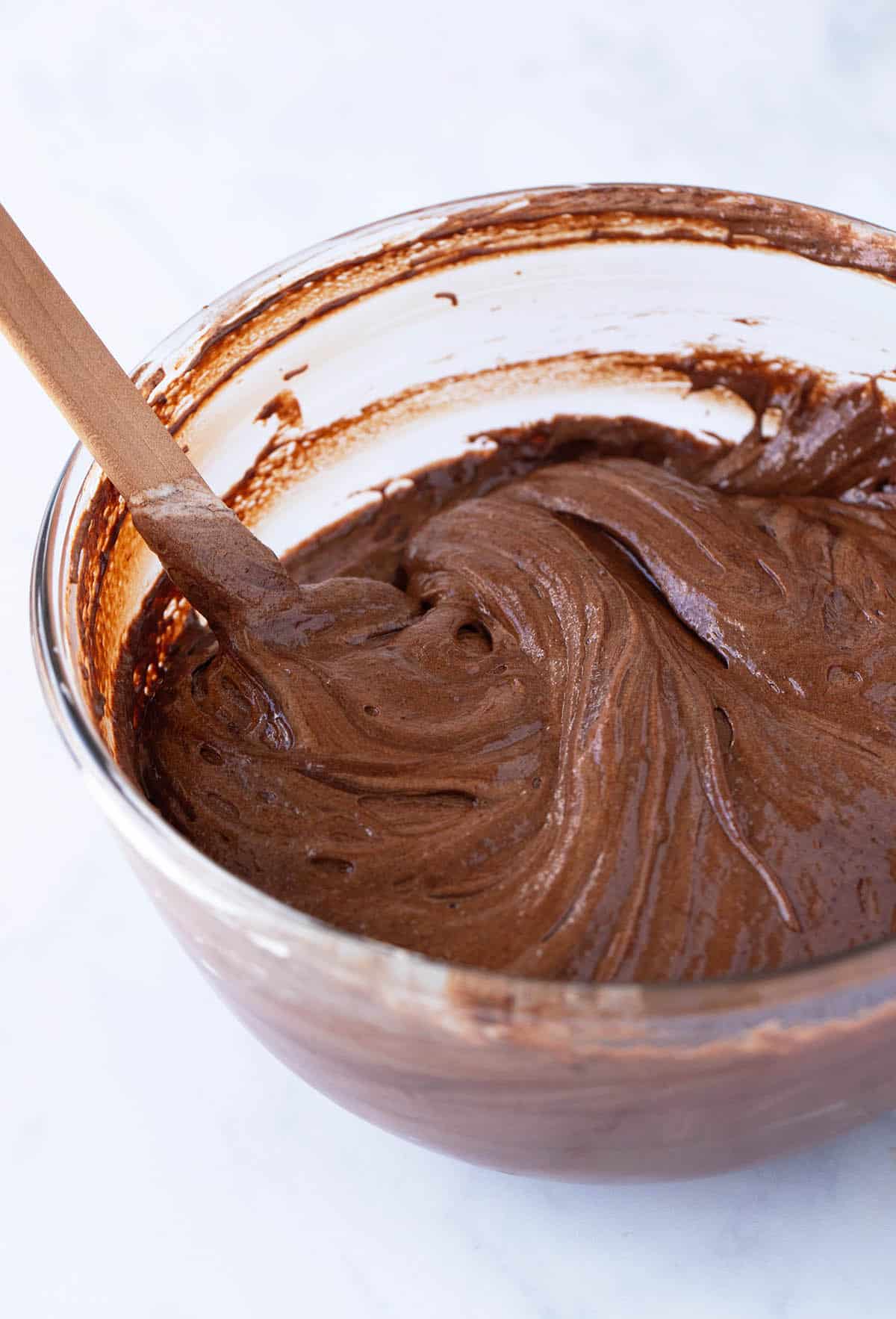 A glass bowl full of chocolate cake batter.
