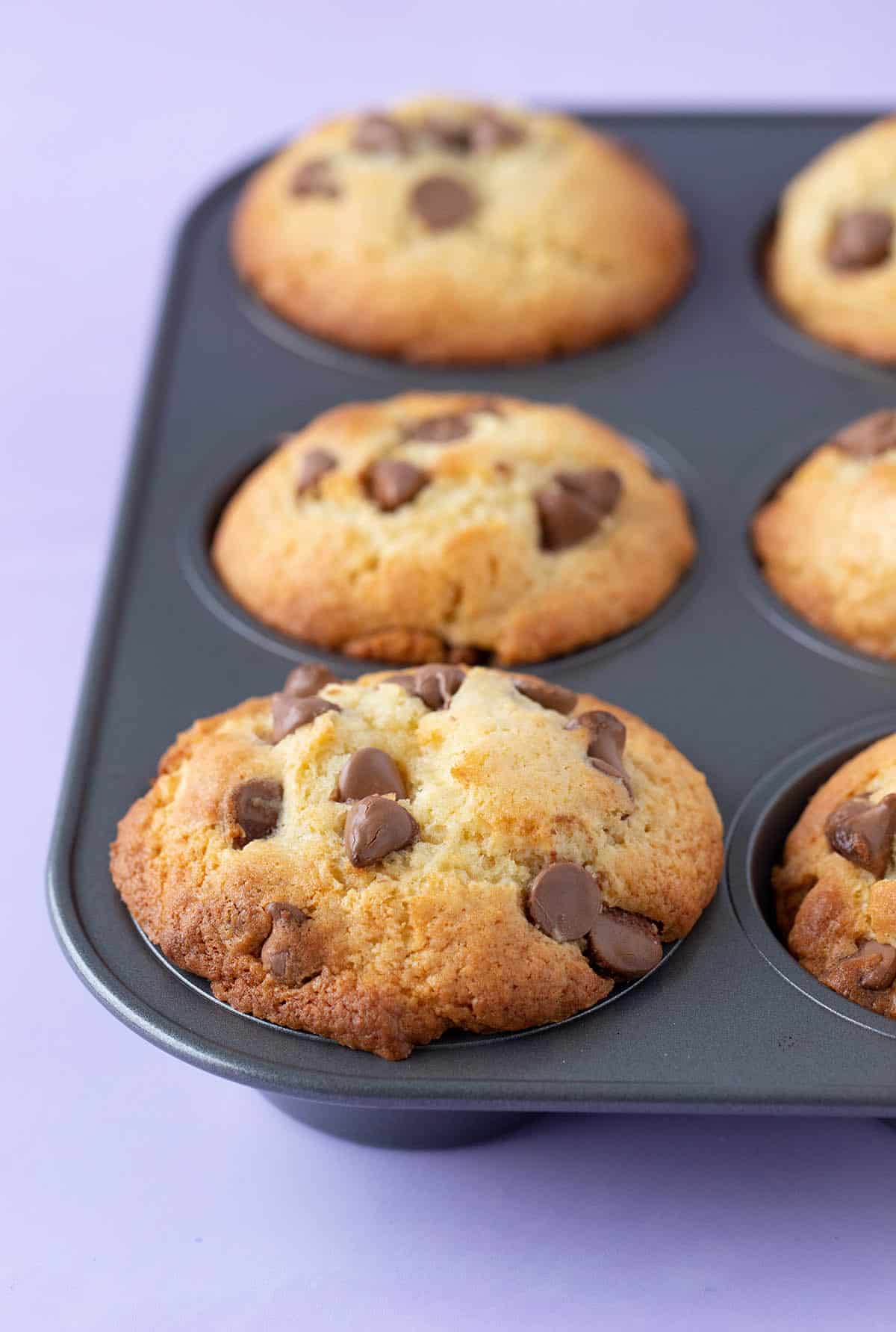 A muffin pan filled with high top Chocolate Chip Muffins.