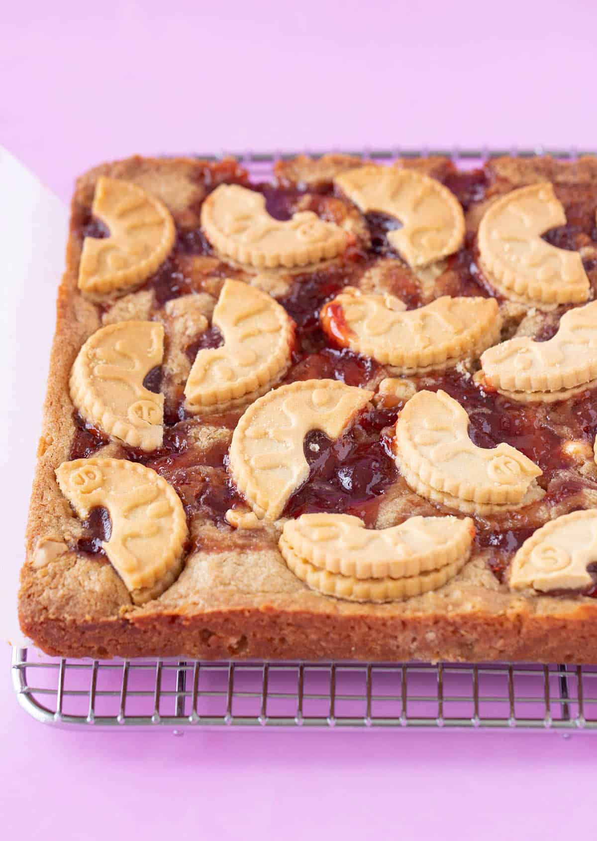 Close up of a homemade Jammie Dodger Blondie fresh from the oven, sitting on a cooling rack.