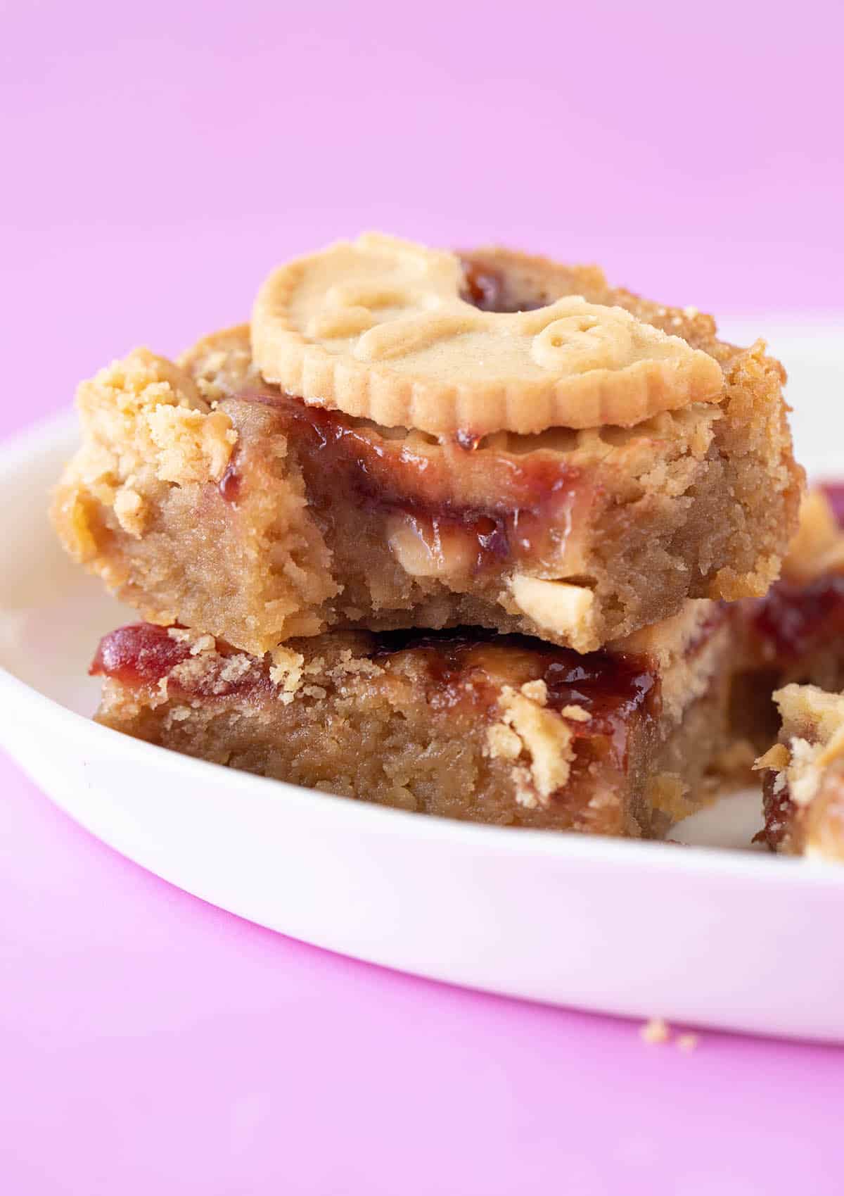 Homemade Jammie Dodger Blondie with a bite taken out of it sitting on a white plate.
