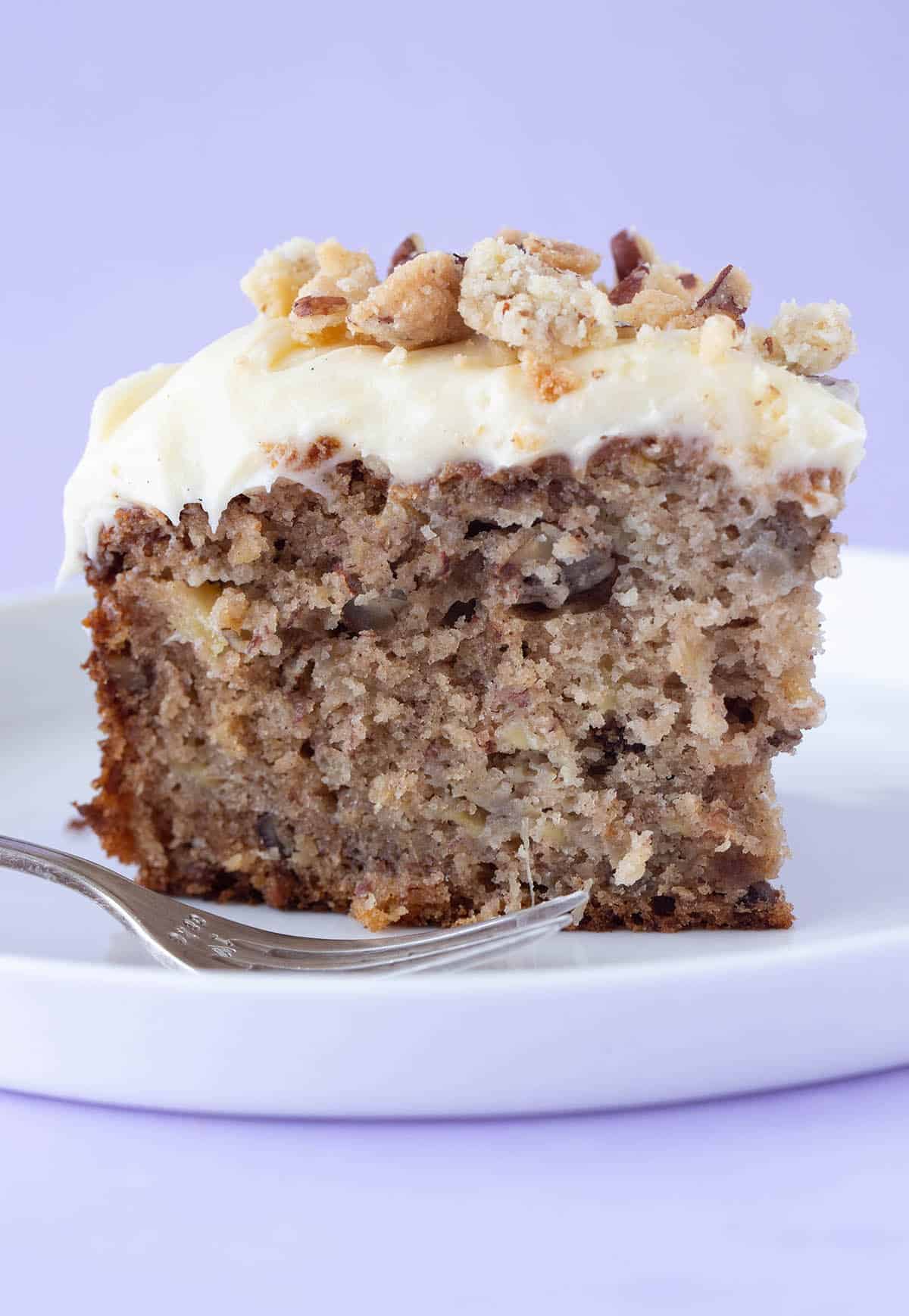 A big slice of Hummingbird Cake on a white plate with a cake fork.