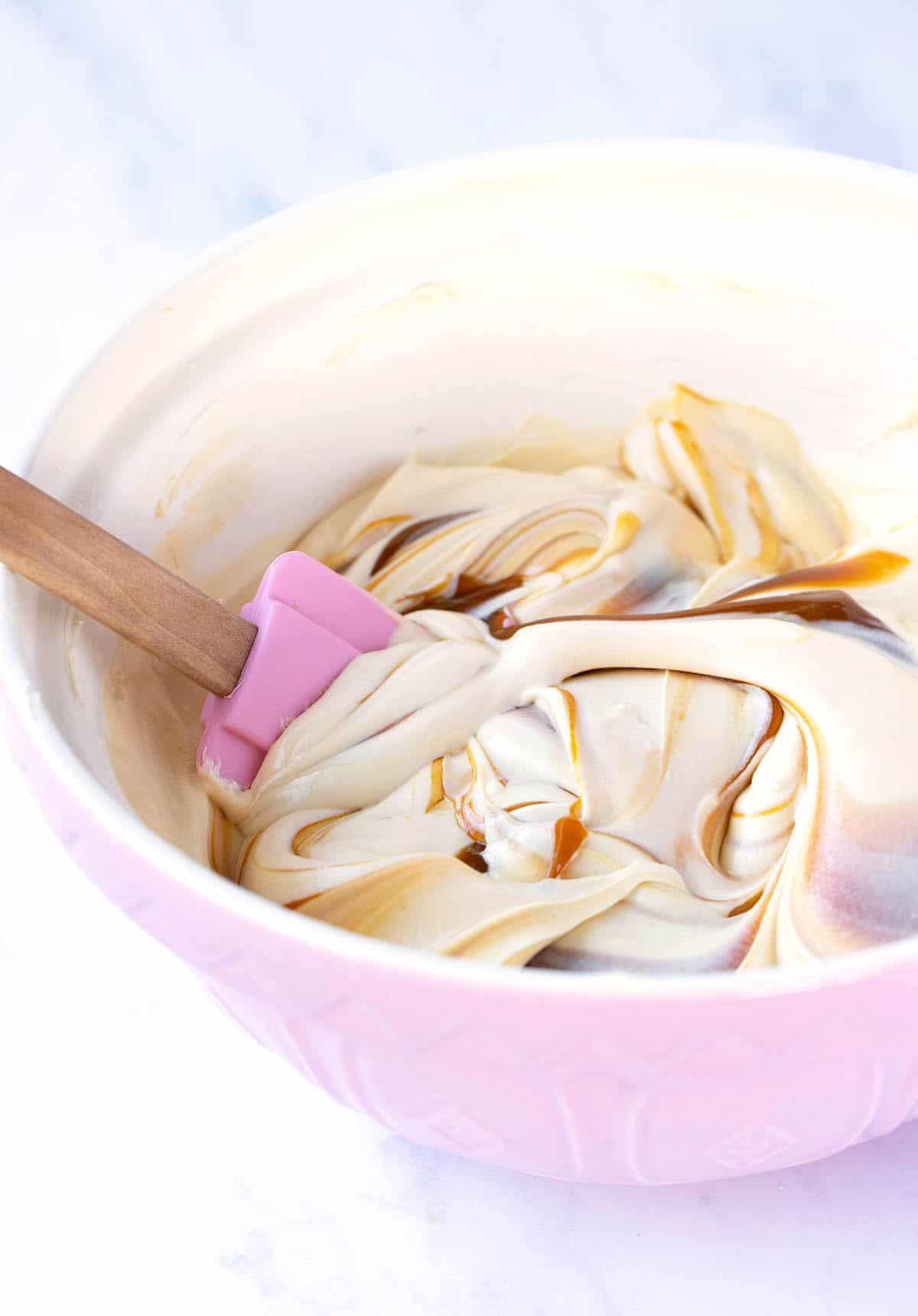 A pink bowl filled with creamy caramel cheesecake.