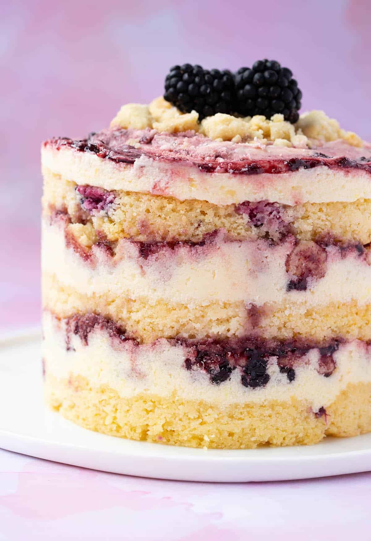A stunning three layer Lemon Blackberry Cake on a white plate. 