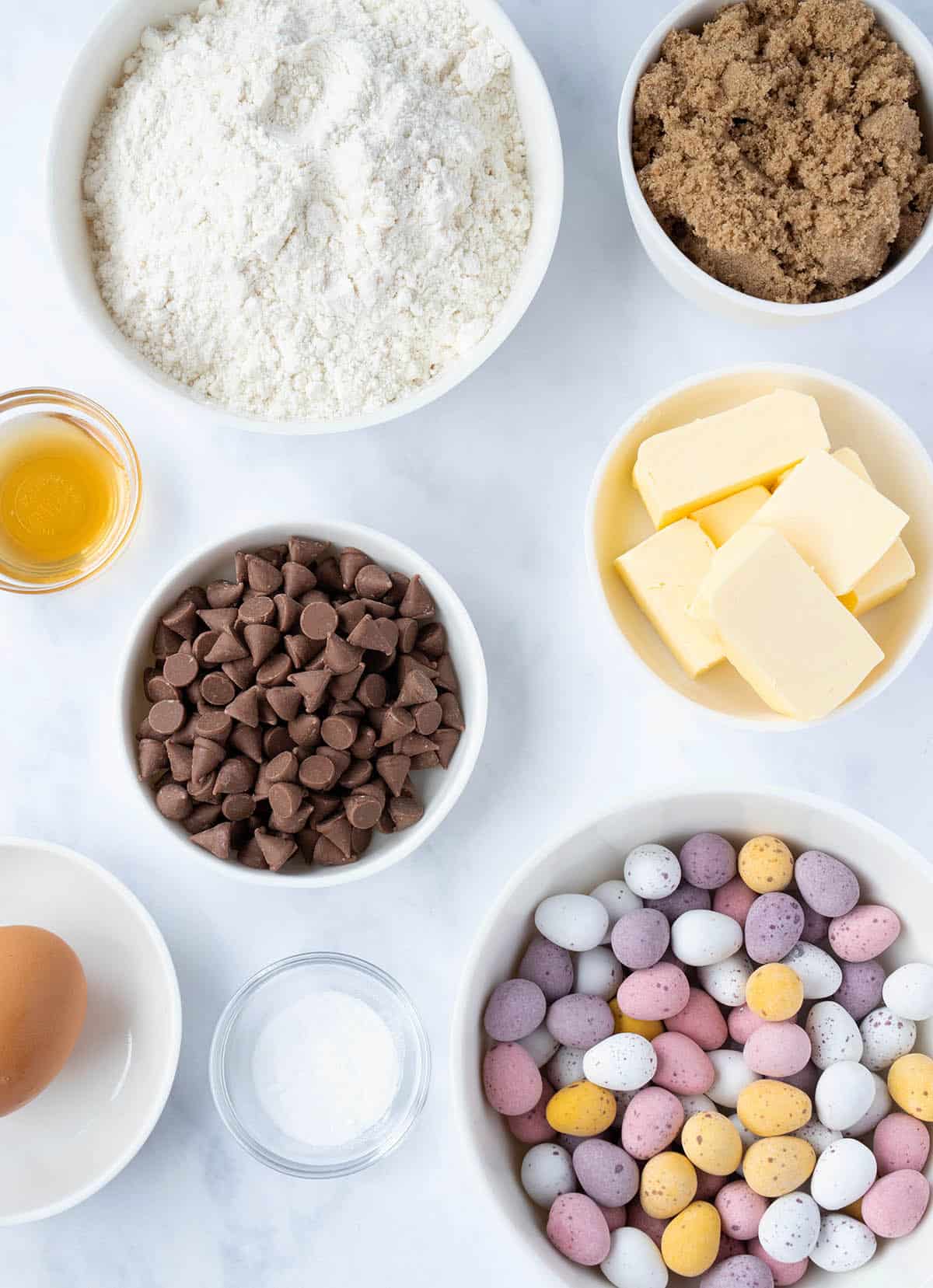 All the ingredients needed to make Mini Egg Cookies sitting on a marble backdrop.