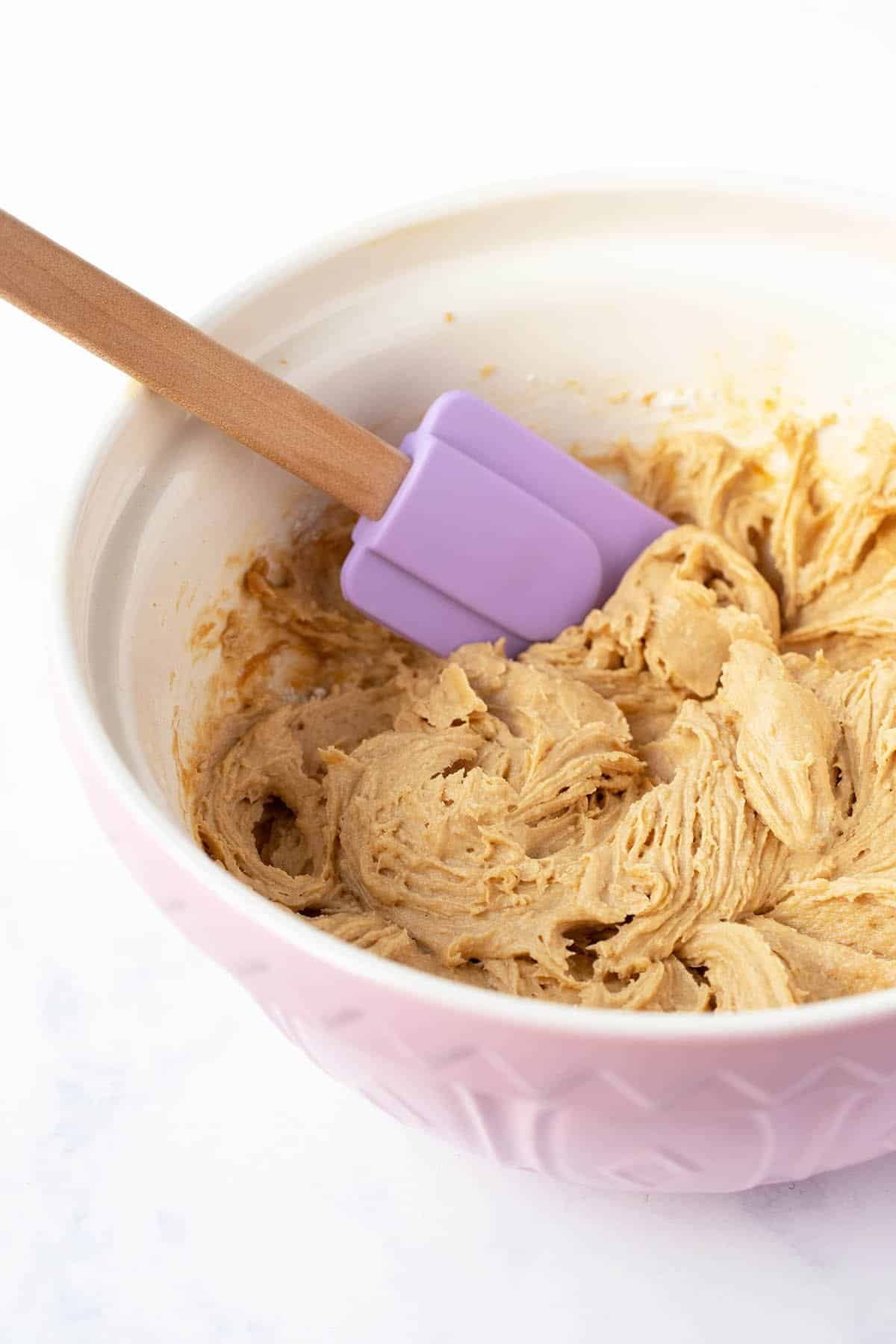 A pink mixing bowl filled with Biscoff cake batter.