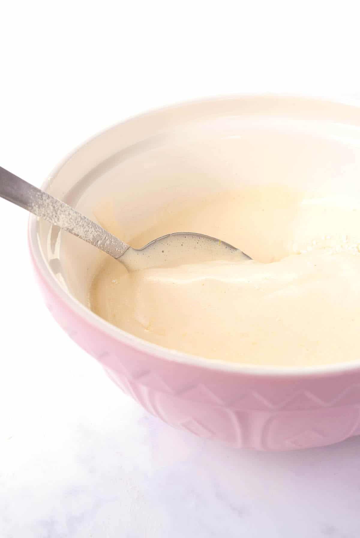 A pink mixing bowl full of fluffy cake batter.